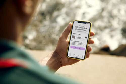 En person håller i sin mobiltelefon och använder Mindlers app för att se över sina anställdas psykiska hälsa