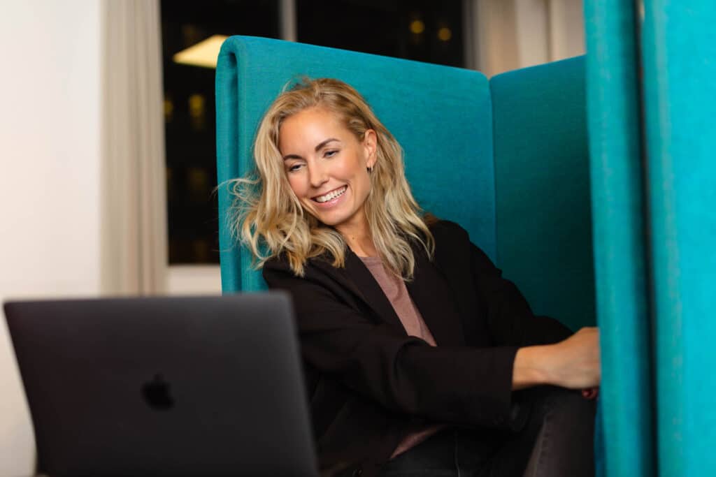 Glad kvinna sittandes i videomöte om rekrytering på sin dator