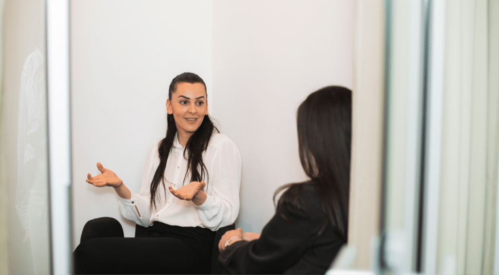 Två kvinnor som sitter i ett mötesrum och håller ett coaching-samtal